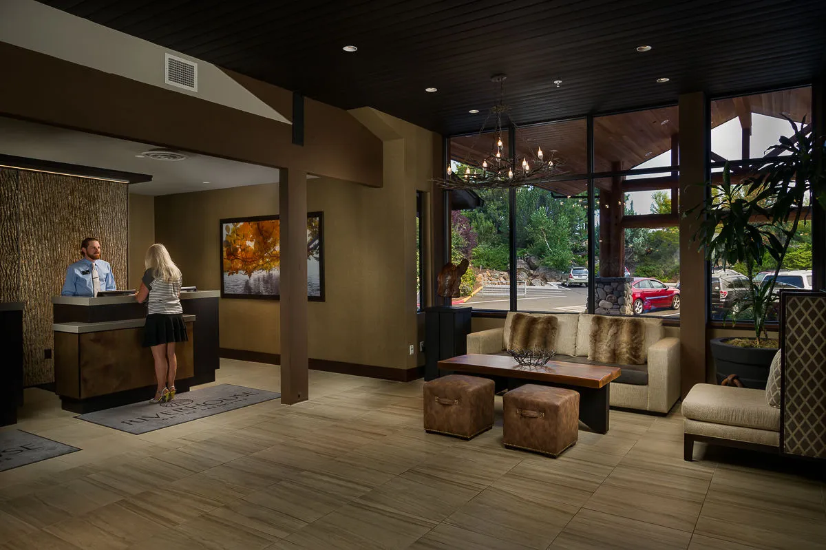 A comfortable, sunlit reception area featuring a welcoming front desk, plush seating, and tasteful artwork. Large windows flood the space with light, creating an inviting atmosphere for guests upon arrival or while relaxing in a communal space.